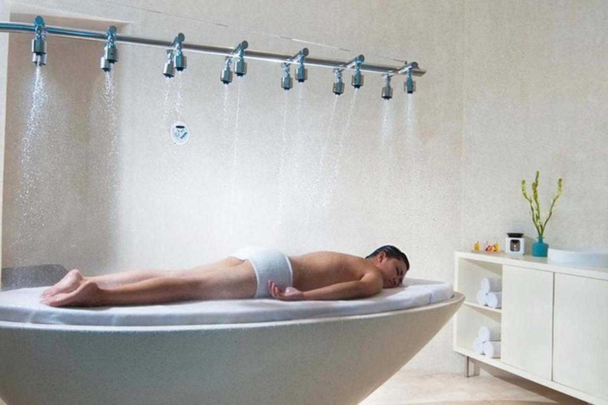 Un hombre acostado en una bañera en un baño.