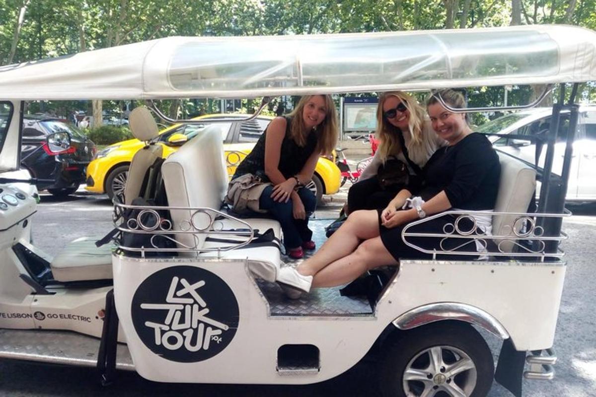 tri žene sjede na stražnjoj strani golf kolica