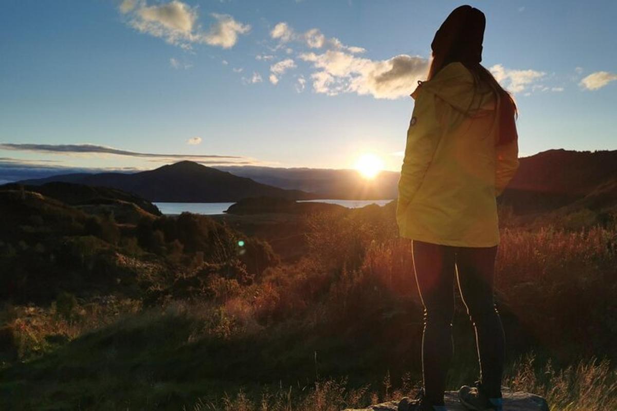 a woman standing on a rock watching the sunset