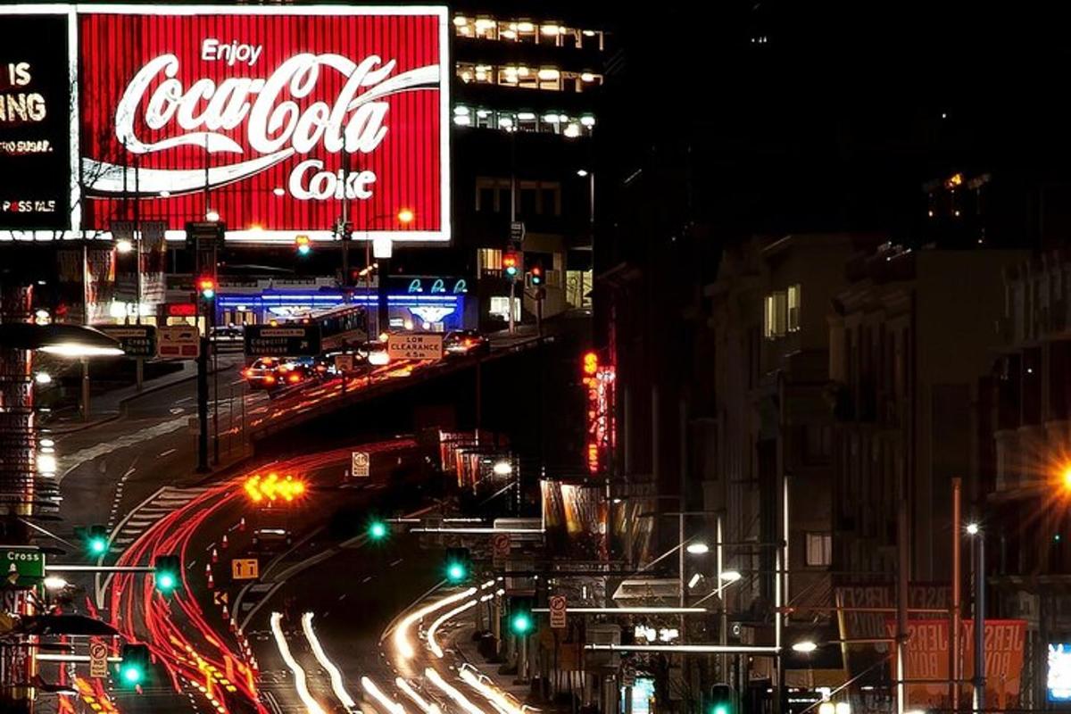 Rušná městská ulice v noci s cedulí Cocacoly