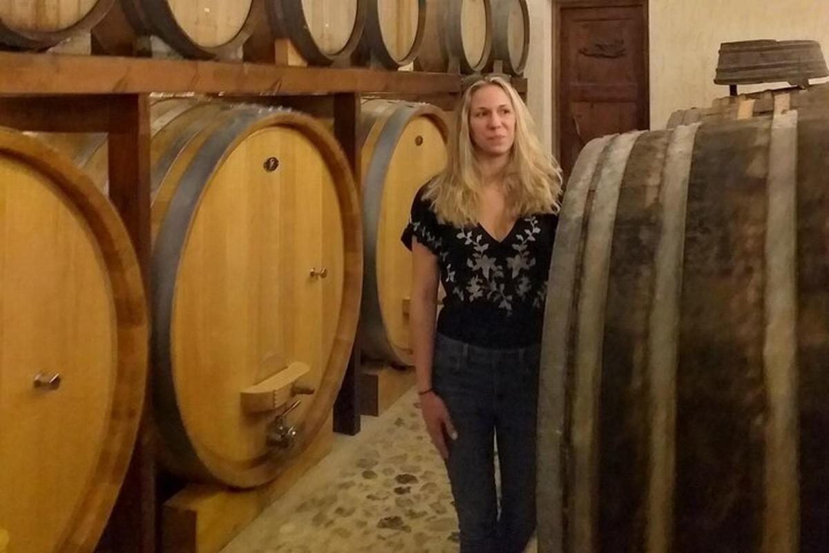a woman standing next to a bunch of wine barrels