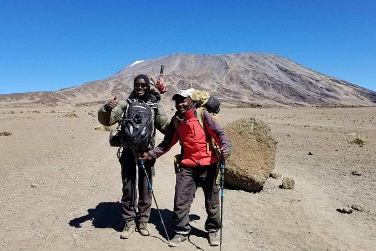 tre personer står i ørkenen med et fjell i bakgrunnen