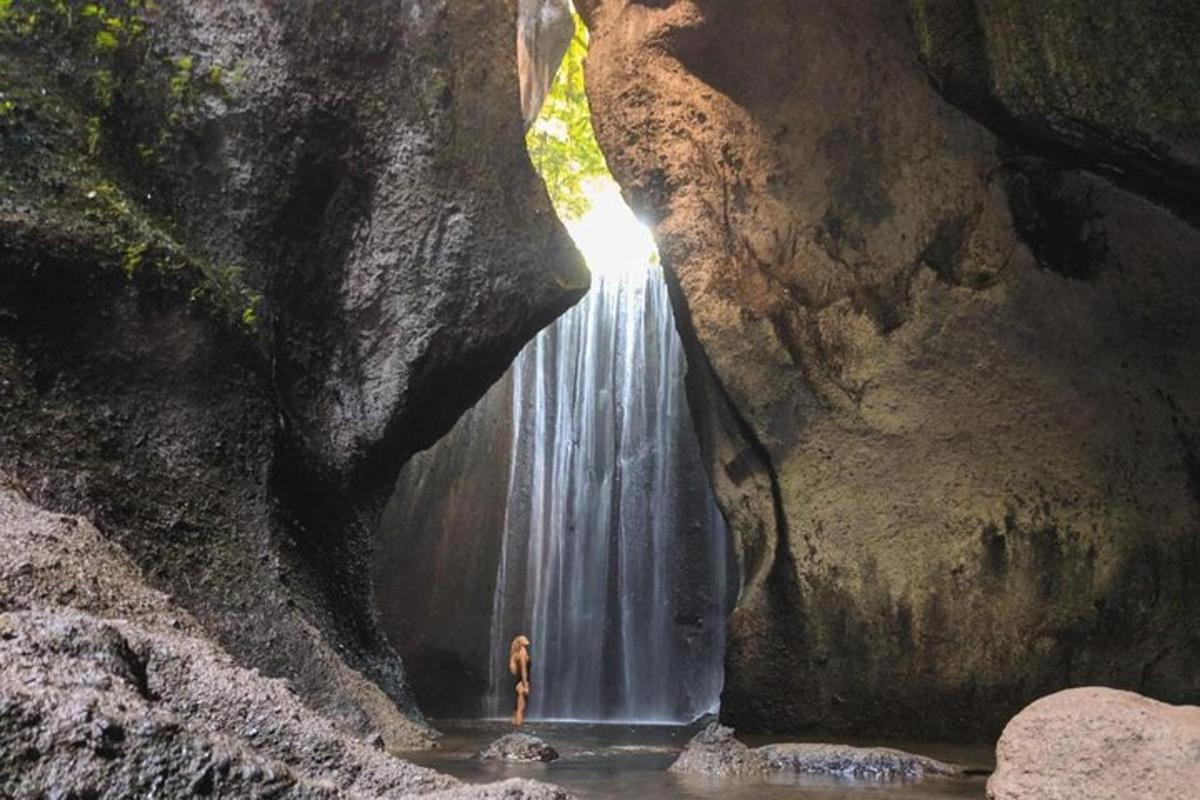 maður stendur fyrir framan foss í helli