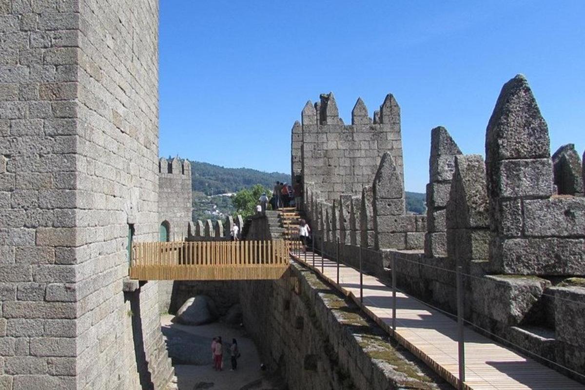 uma vista de um castelo com pessoas caminhando em uma ponte