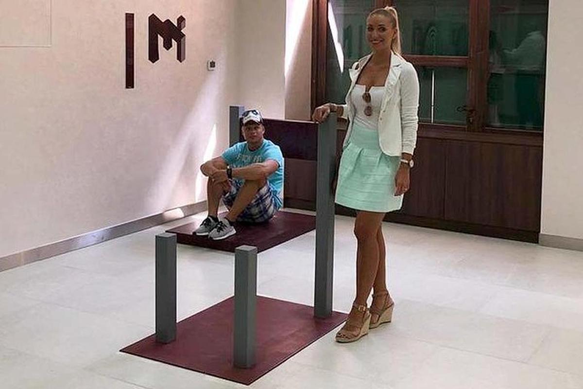 a woman standing next to a man sitting on a bench