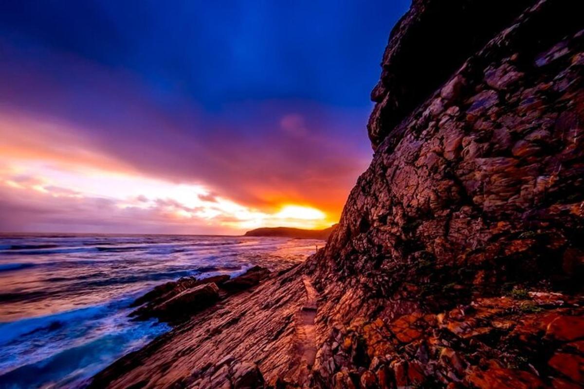 um pôr do sol sobre o oceano com uma costa rochosa