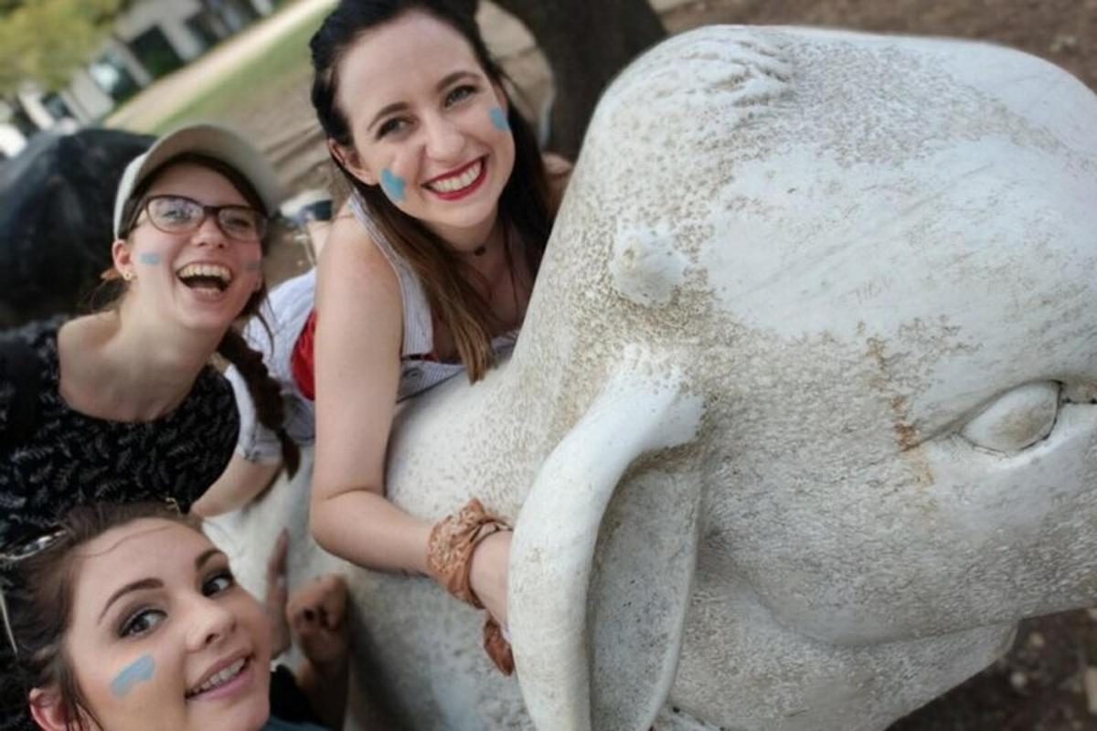 two girls standing next to a statue of a bear