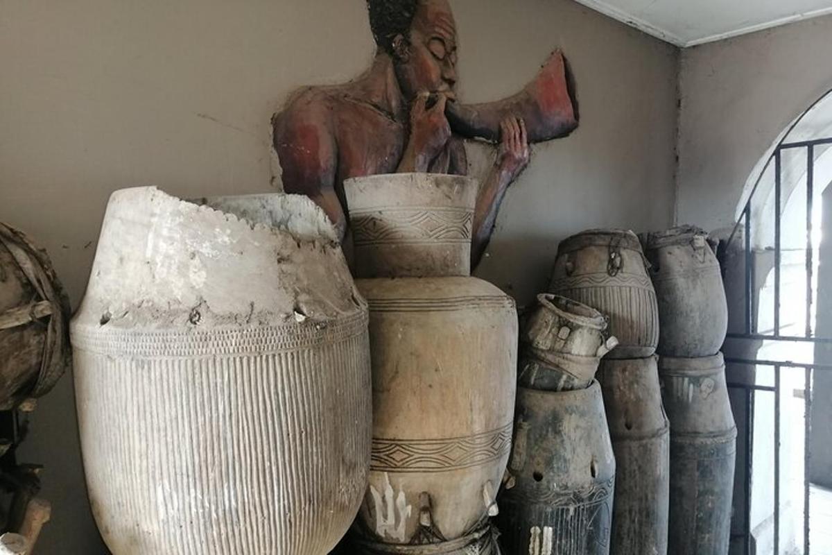 uma estátua de um homem em pé ao lado de um monte de vasos
