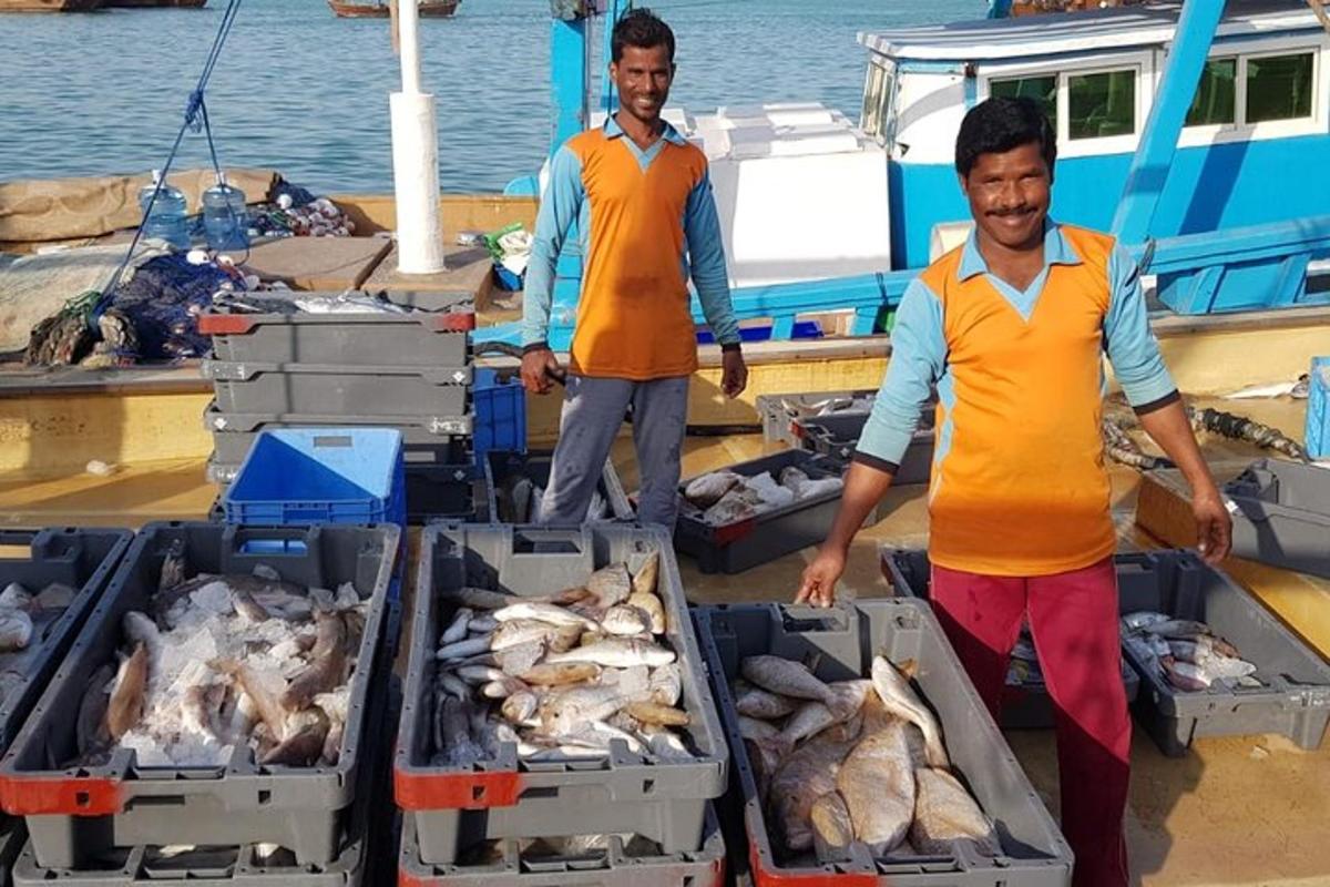 رجلان يقفان على قارب مع صناديق الأسماك