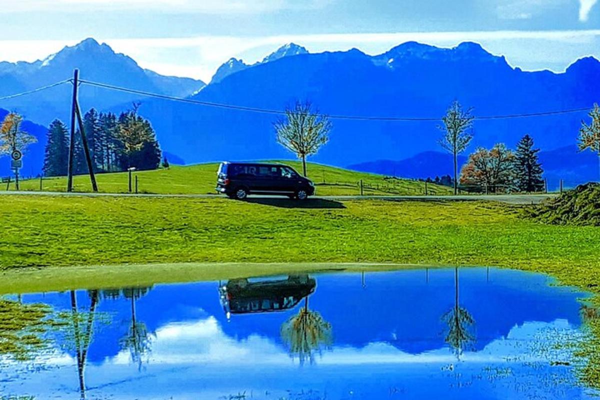 a car parked in a field with a reflection in a pond
