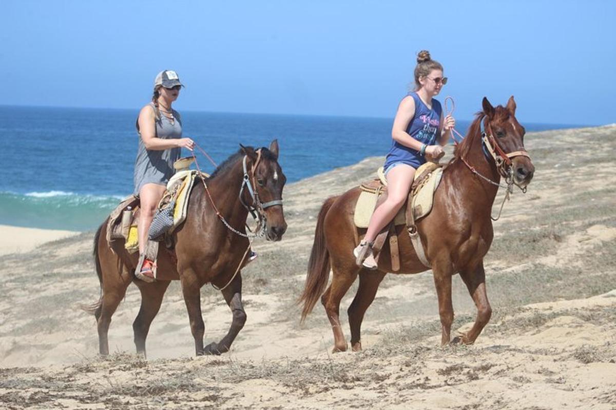 due donne stanno cavalcando sulla spiaggia