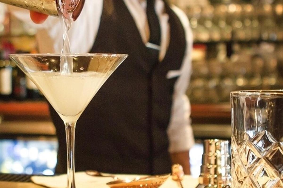 a bartender is pouring a drink into a martini glass