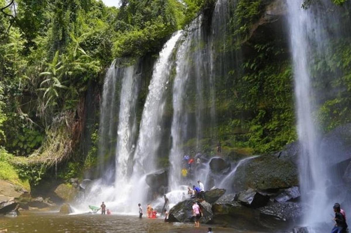 gente parada en el agua cerca de una cascada