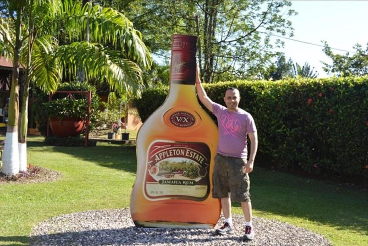 muž stojaci vedľa veľkej fľaše alkoholu