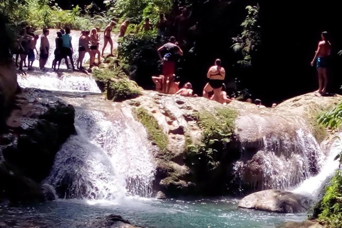sekumpulan orang dalam pakaian mandi berdiri di air terjun