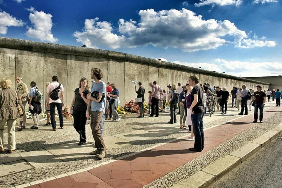 una folla di persone in piedi vicino a un muro