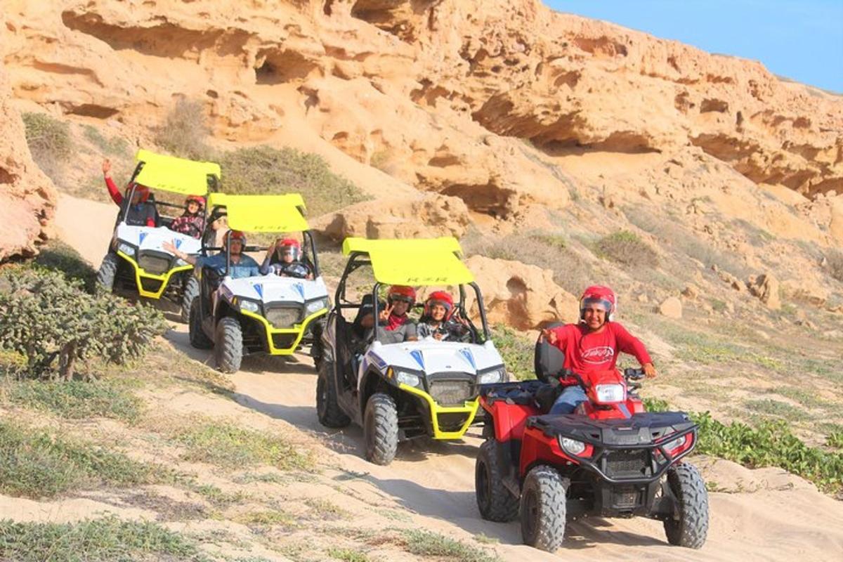 un grup de oameni care călătoresc cu ATV-uri pe un drum de pământ
