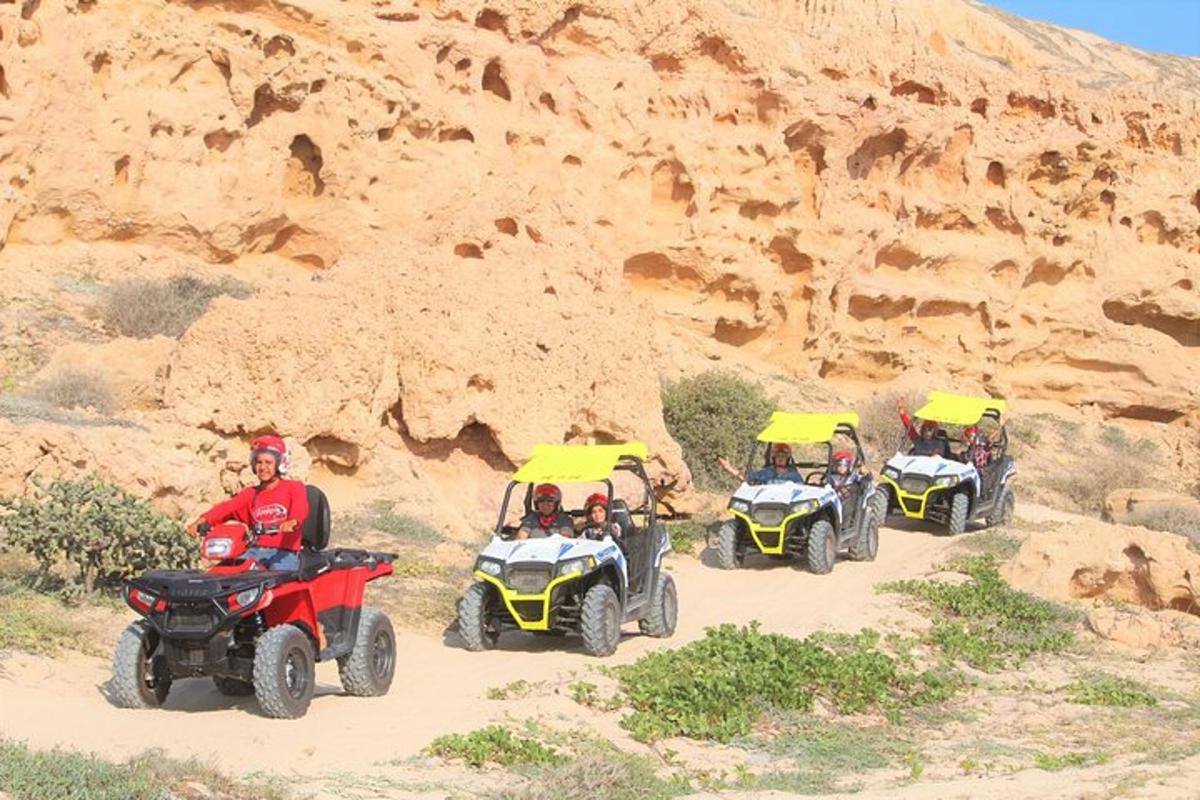un grup de oameni care călătoresc cu ATV-uri pe un drum de pământ