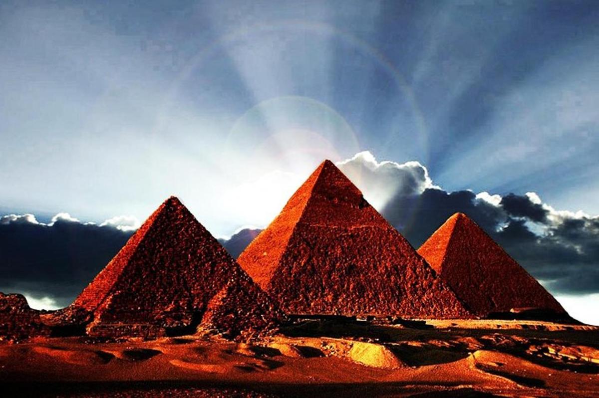 un groupe de pyramides dans un désert sous un ciel nuageux