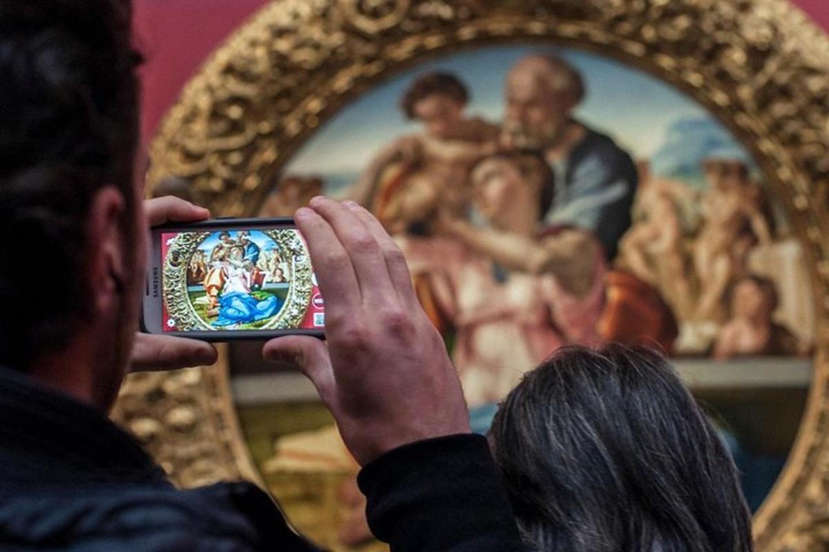 muž fotící obraz mobilním telefonem