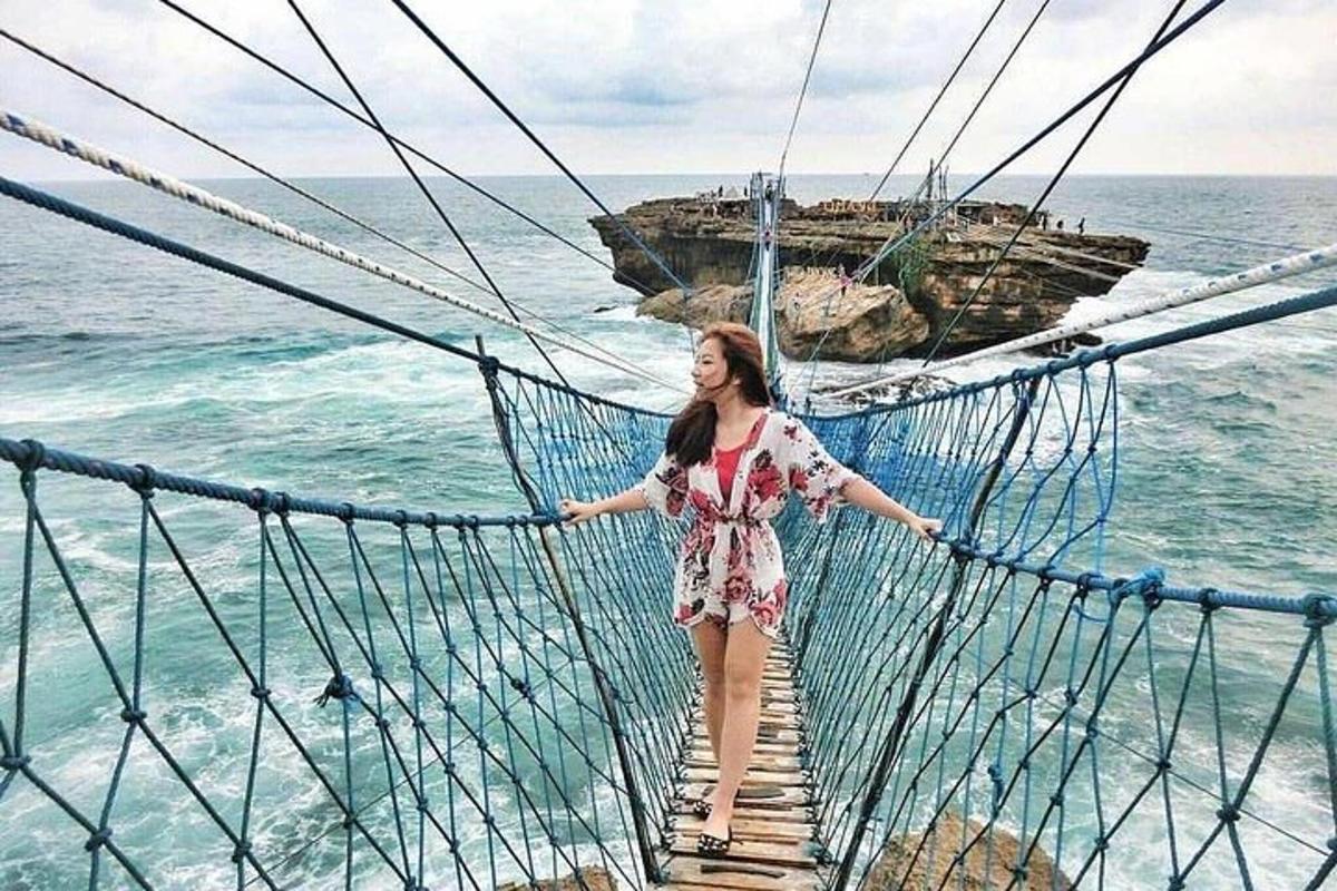 een vrouw die op een hangbrug over de oceaan staat