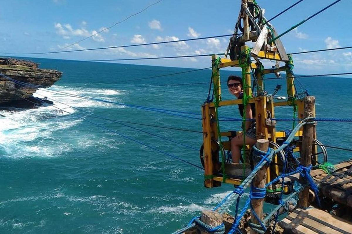 un uomo seduto su un'altalena di corda sopra l'oceano