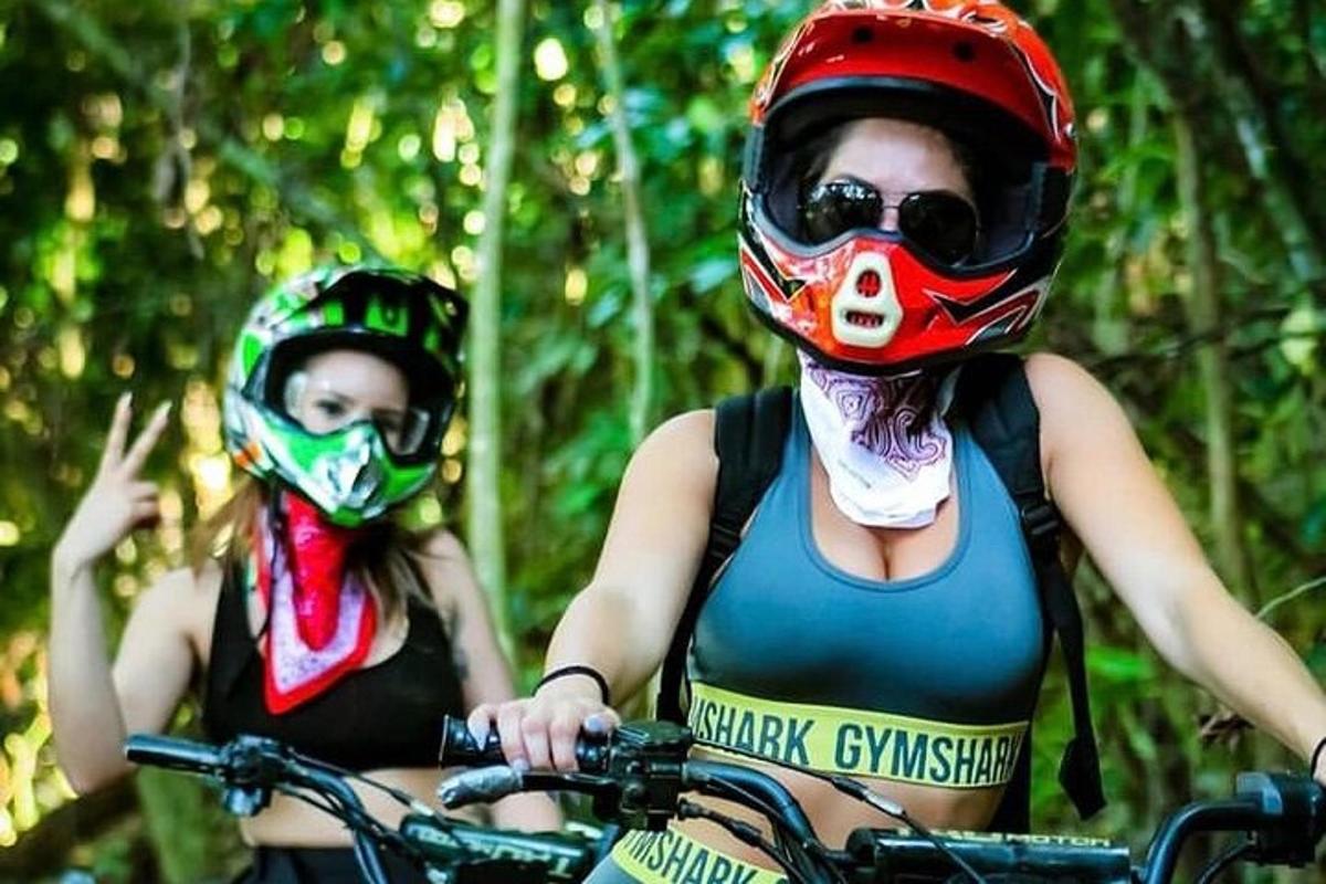 dua wanita memakai topeng dan topi keledar menunggang basikal
