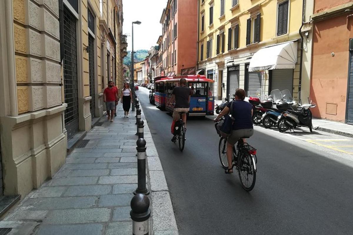 Dos personas en bicicleta por una calle con un autobús.
