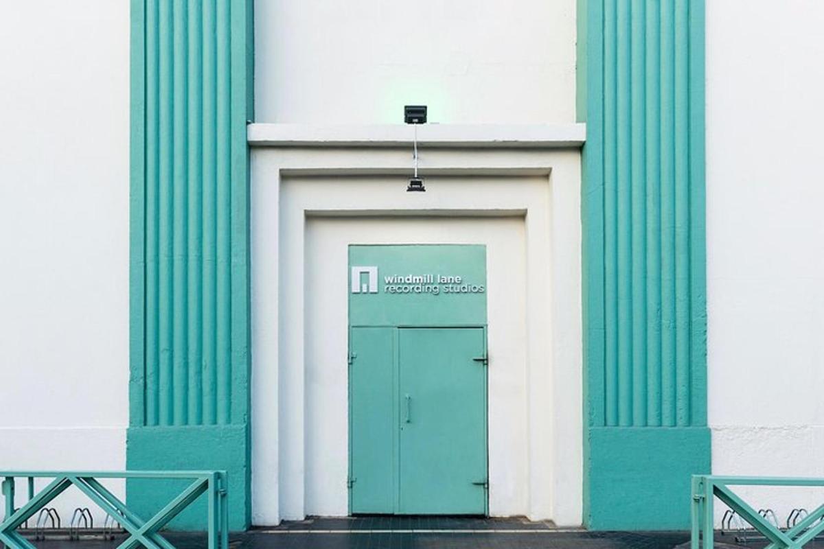a green door in a white building with two benches