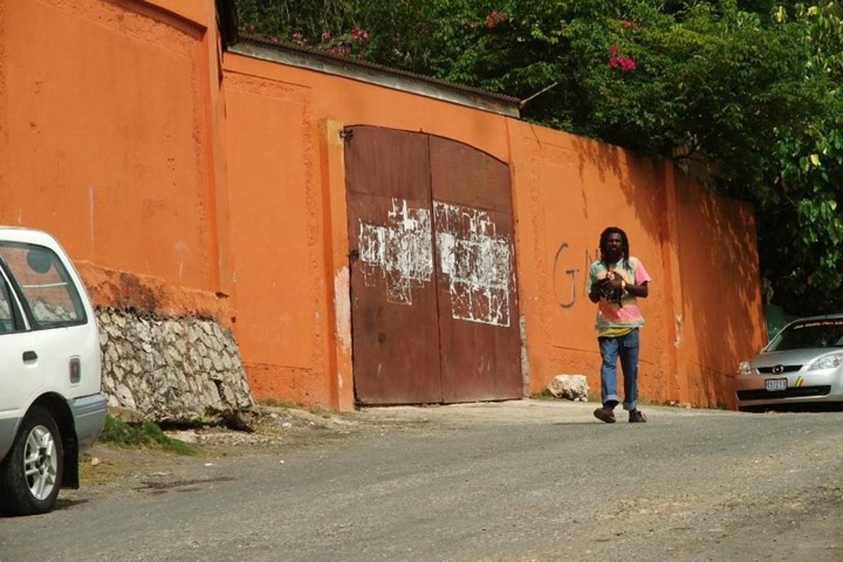 una donna che cammina lungo una strada accanto a un muro arancione