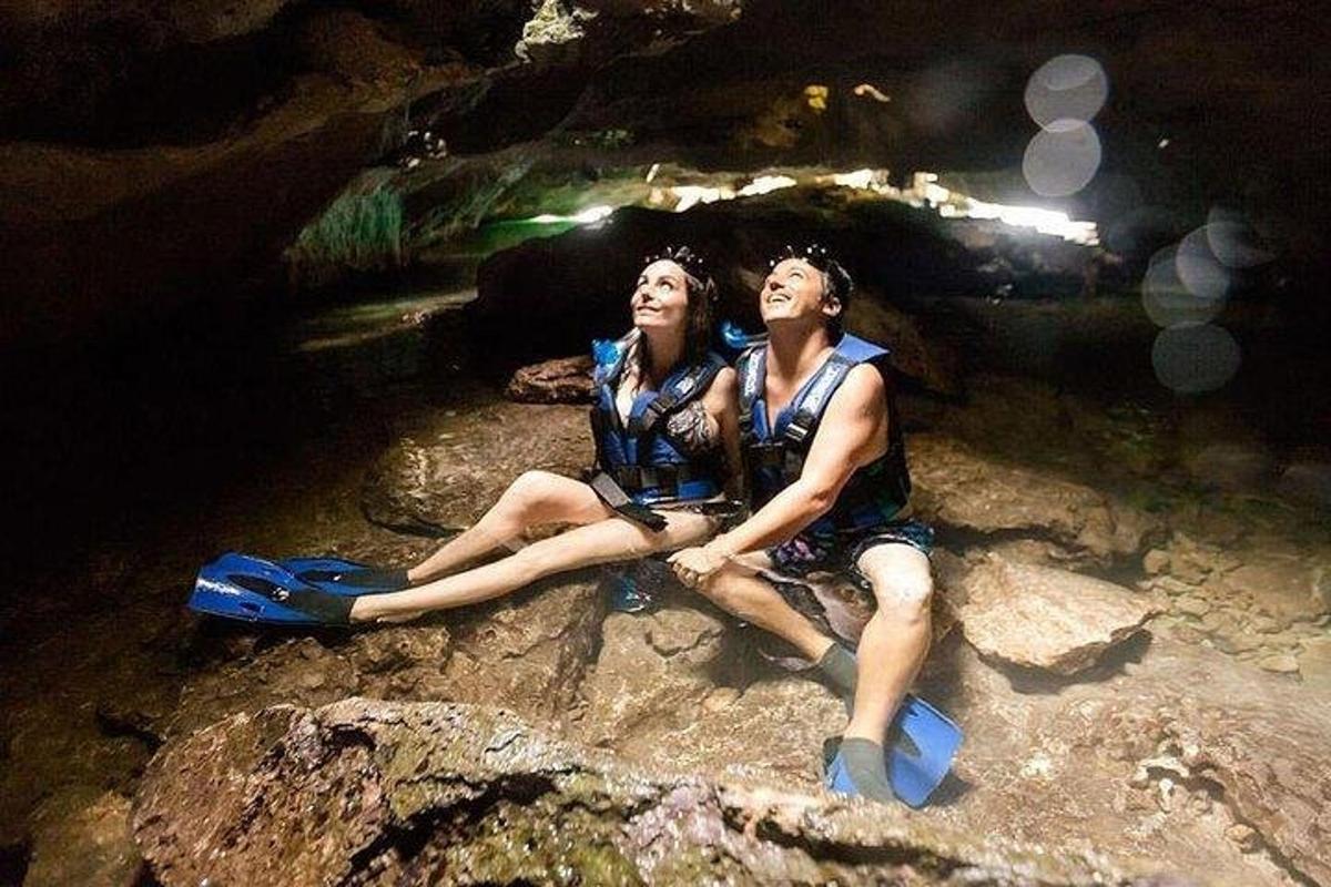 two people sitting on a rock in a cave
