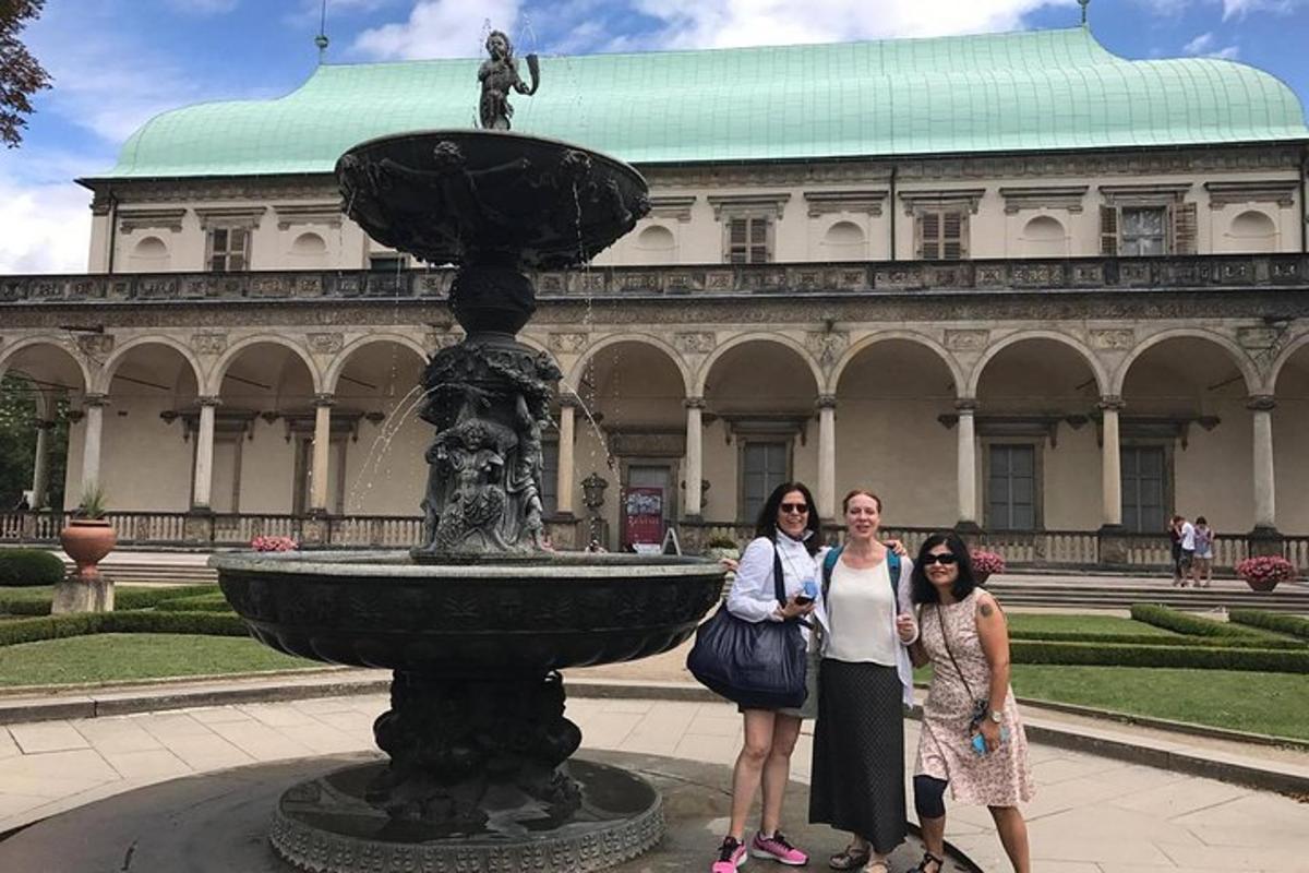 drei Frauen stehen neben einem Brunnen vor einem Gebäude
