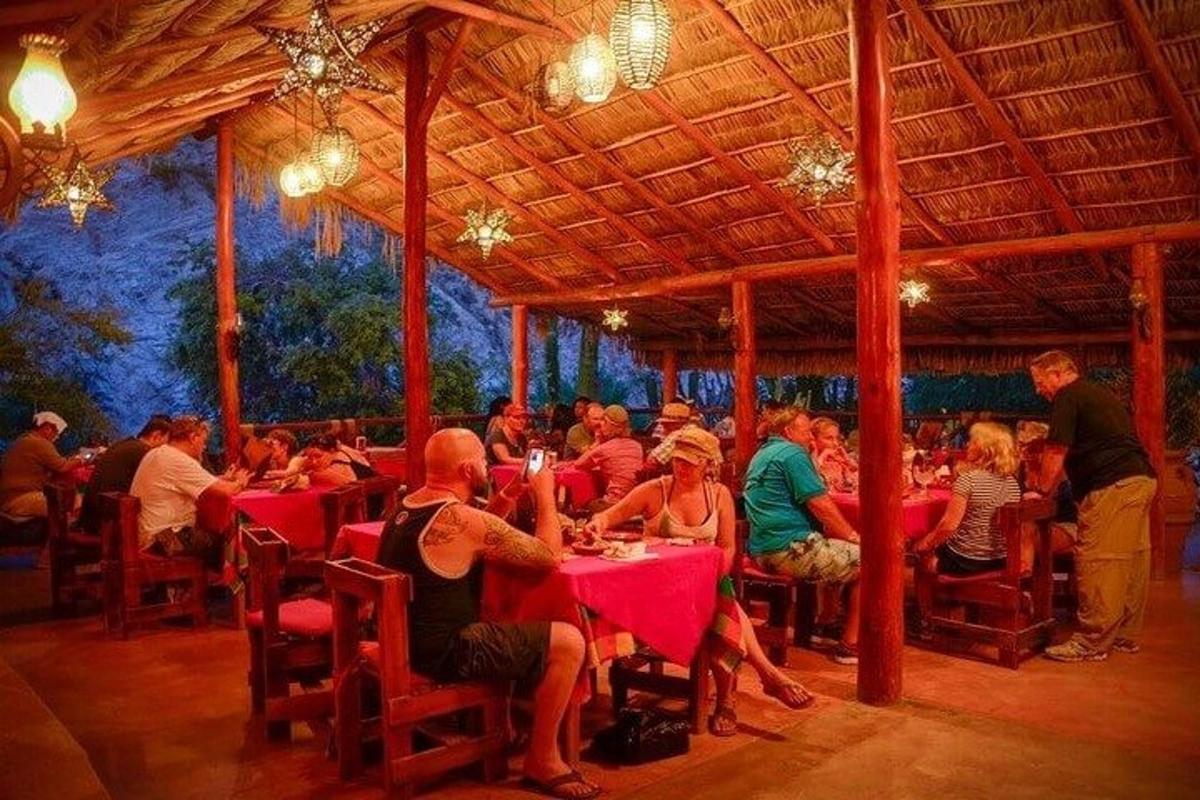 cilvēku grupa, kas sēž pie galdiņiem restorānā