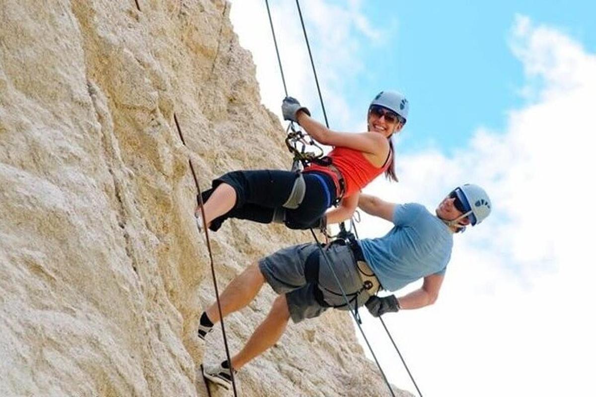 a man and woman rock climbing on a cliff
