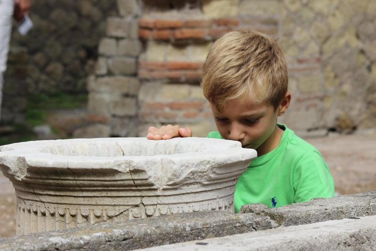 a young boy is looking into a stone planter