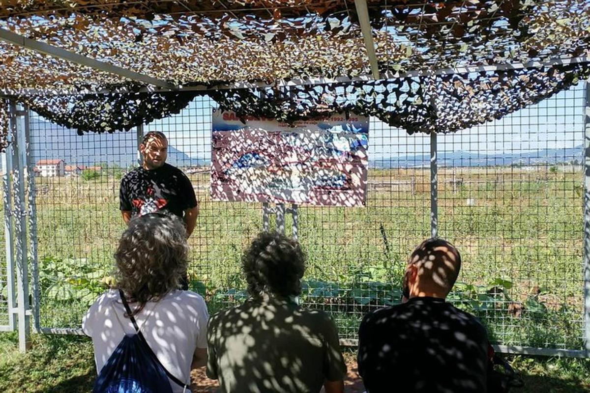 Un grupo de personas observando a un hombre parado debajo de una valla.