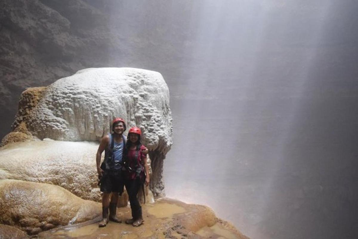 due persone in piedi su una roccia di fronte a una cascata