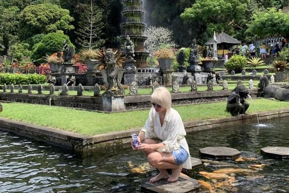una dona asseguda en una roca prop d'un estany en un jardí
