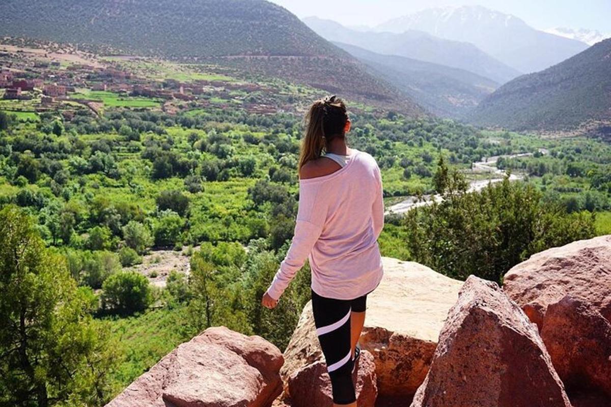 Una mujer parada en la cima de una roca con vista a un valle.