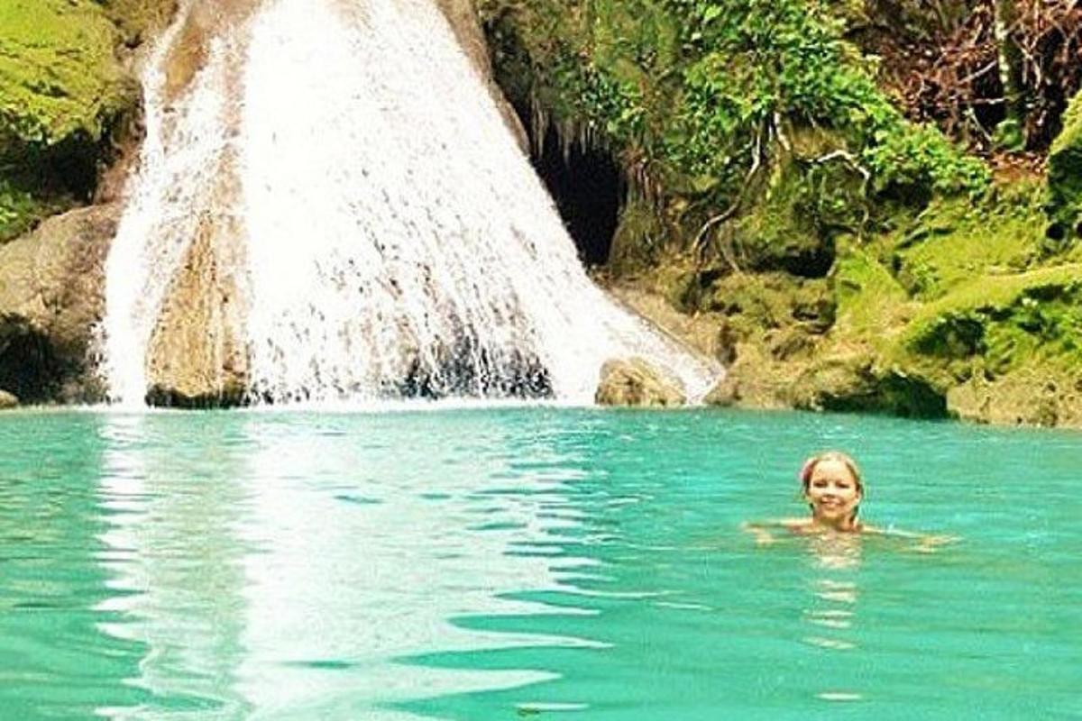 uma mulher nadando em uma piscina em frente a uma cachoeira