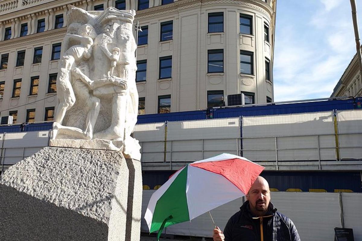 un home que sosté un paraigua davant d'una estàtua