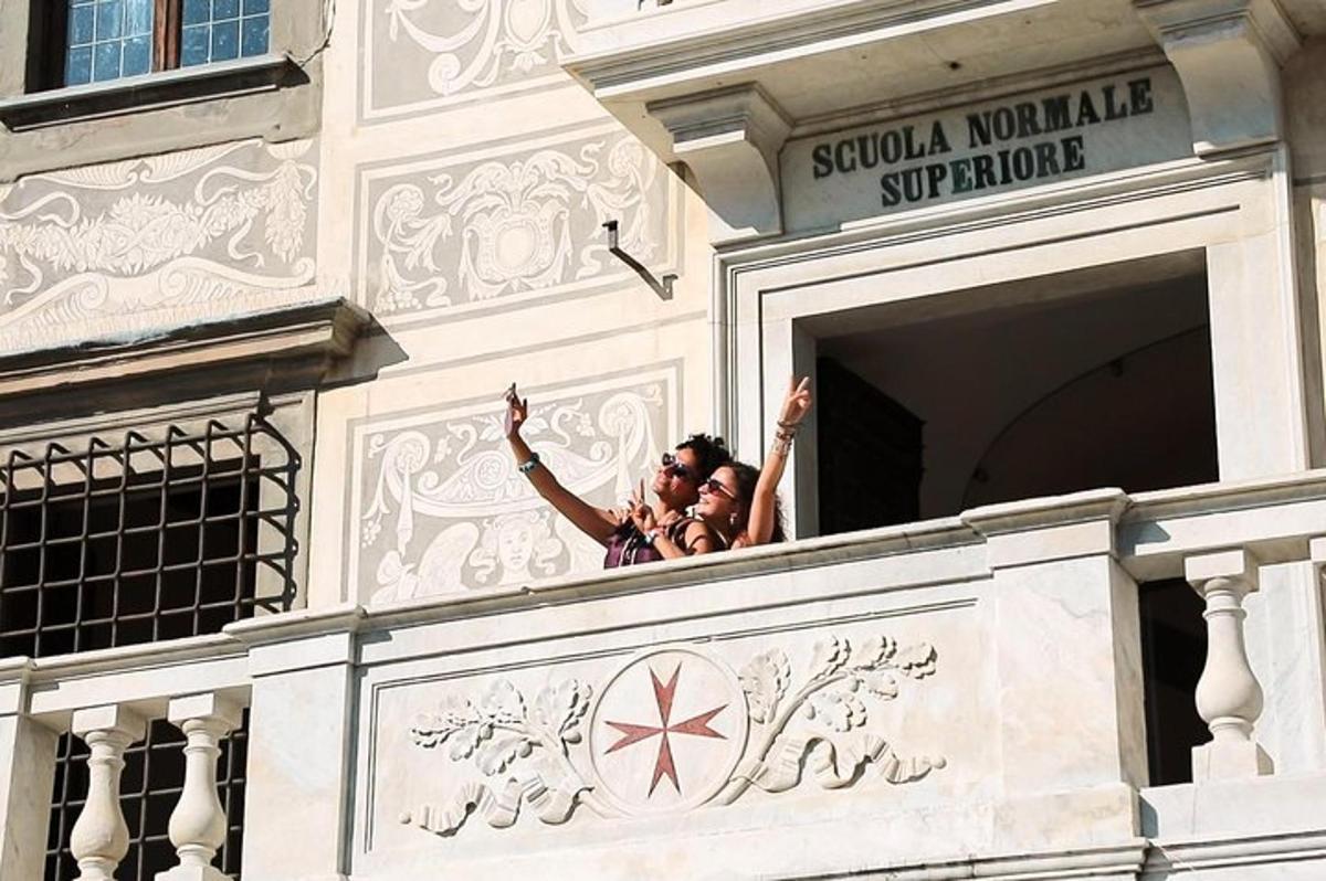 Tres personas saludando desde un balcón de un edificio