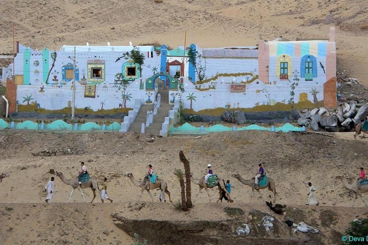 a group of people riding camels in front of a building