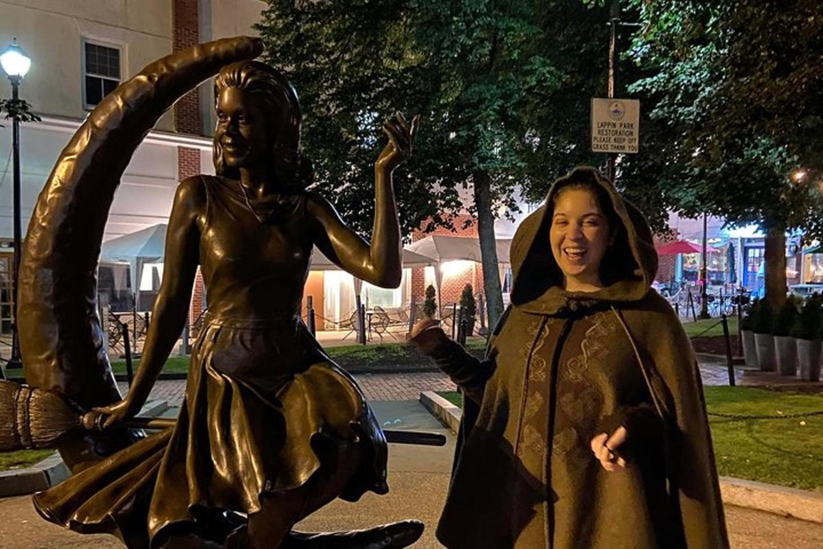 Una mujer parada junto a una estatua de una mujer.