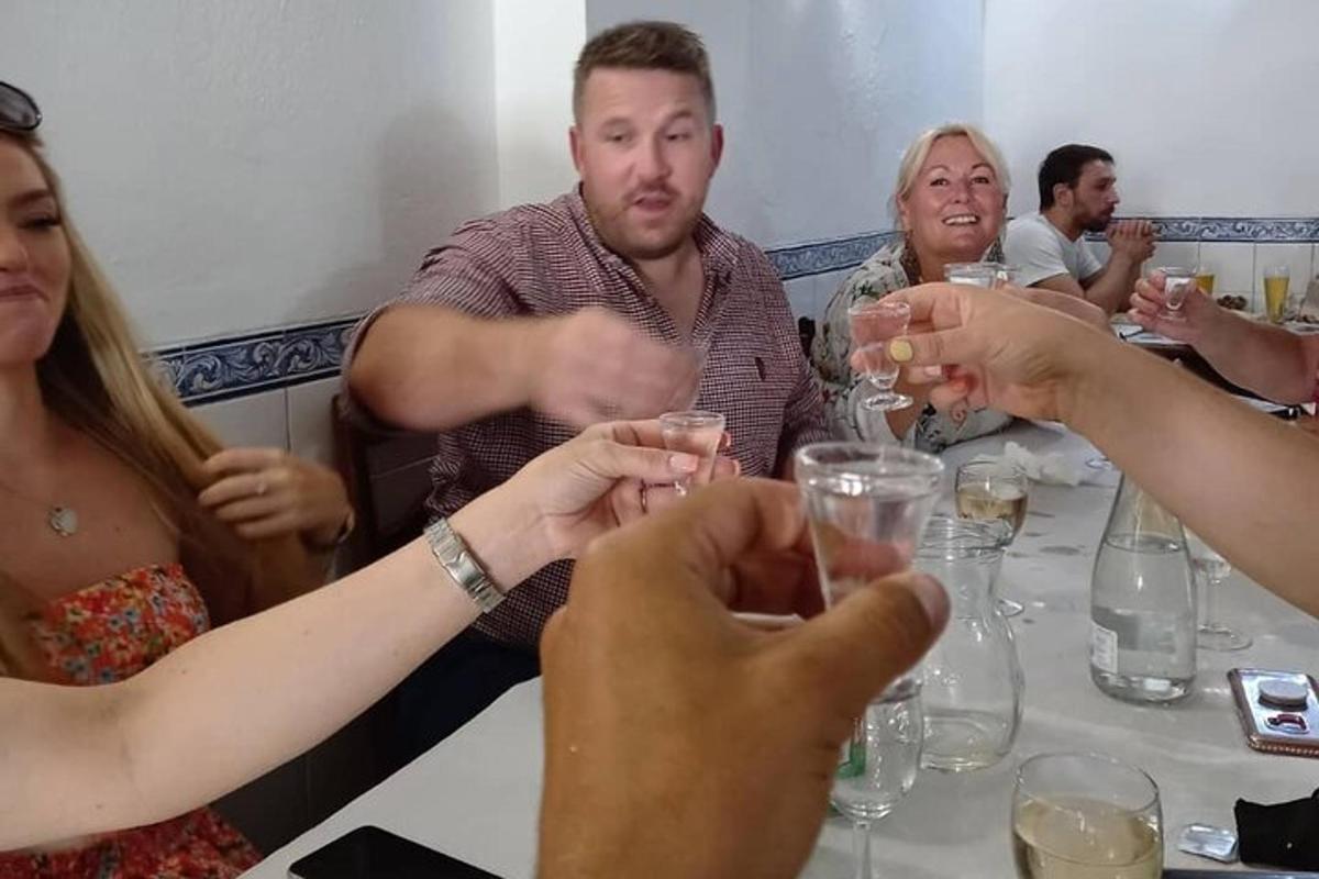 un gruppo di persone sedute attorno a un tavolo che bevono vino