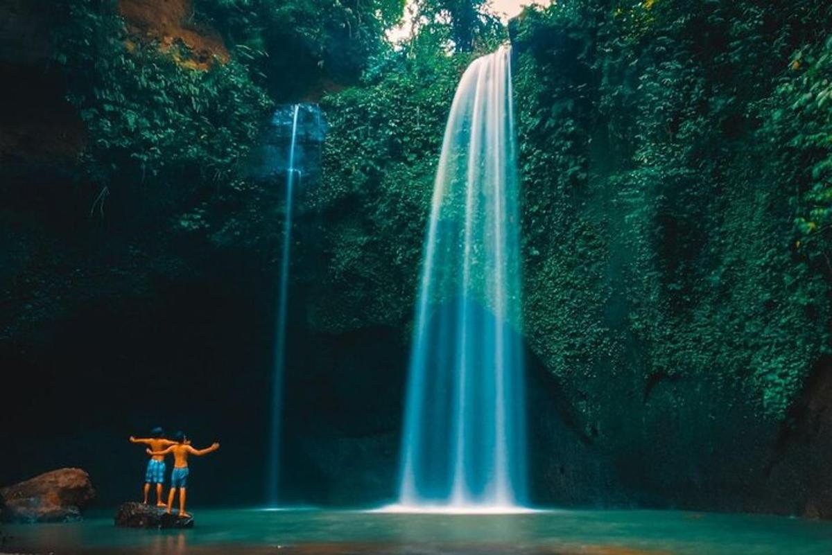 two people standing in front of a waterfall