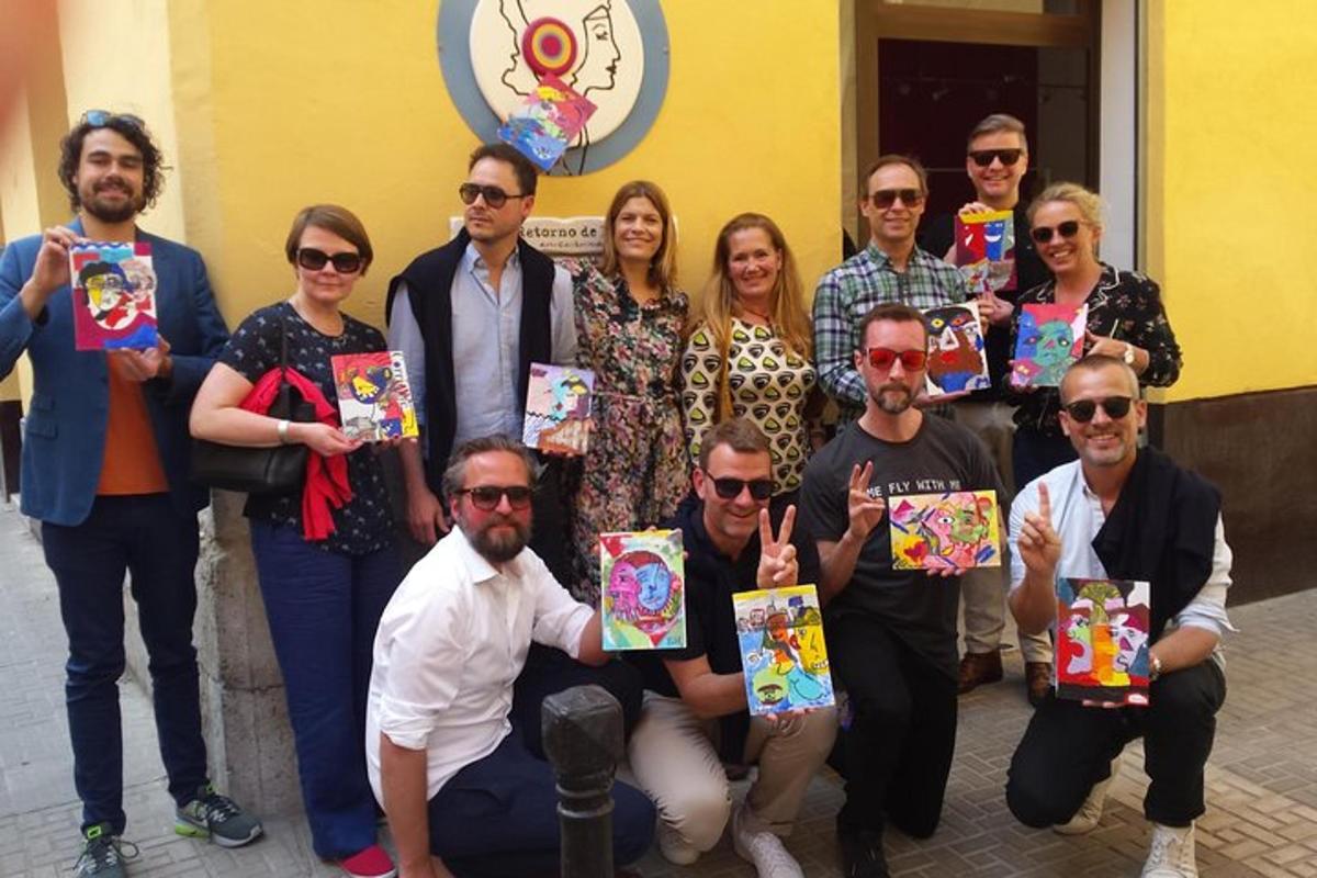 a group of people posing for a picture holding up paintings