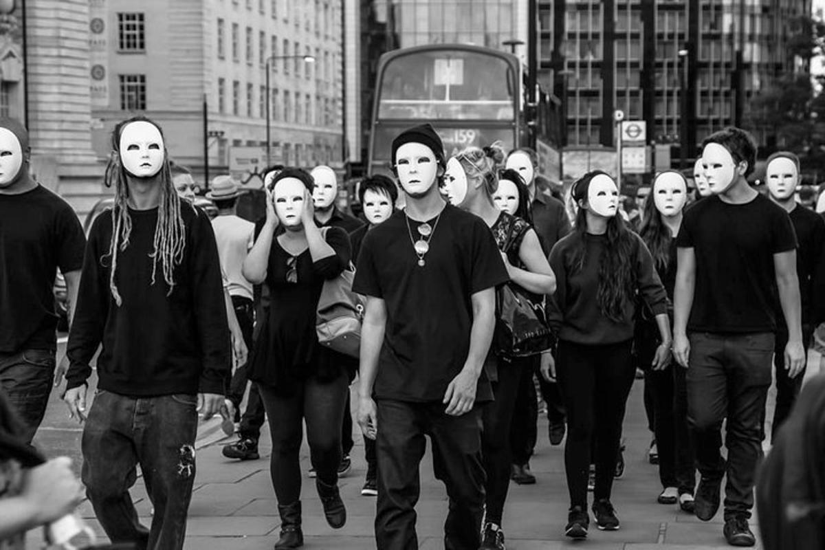 en gruppe mennesker, der går ned ad en bygade med ansigtsmasker