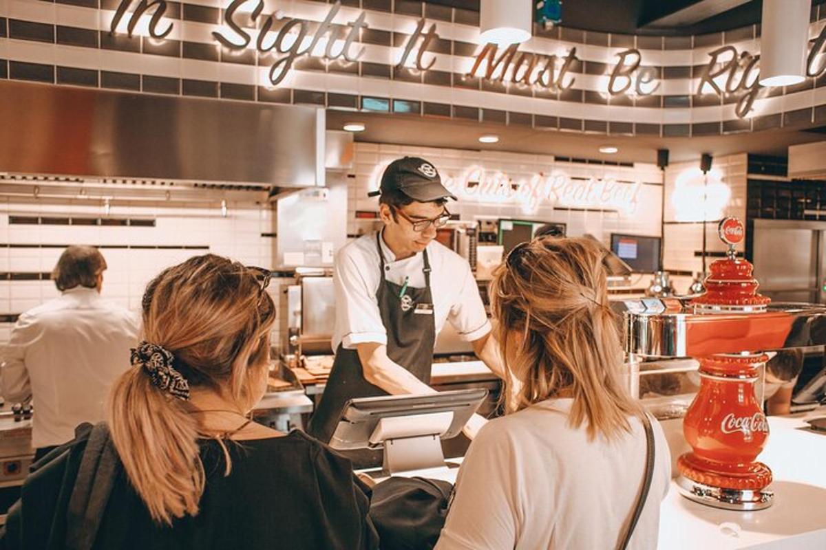 um homem preparando comida em um restaurante com duas mulheres
