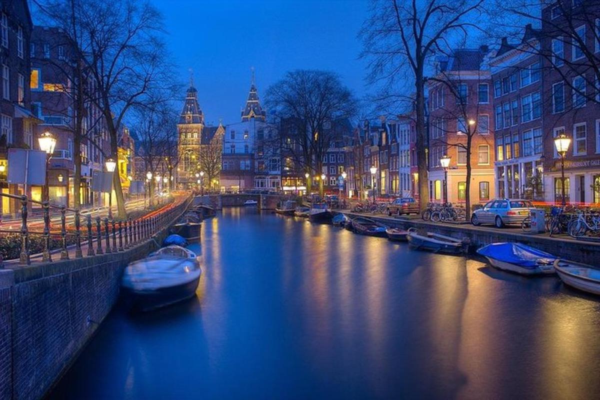 Un río con barcos en una ciudad por la noche.